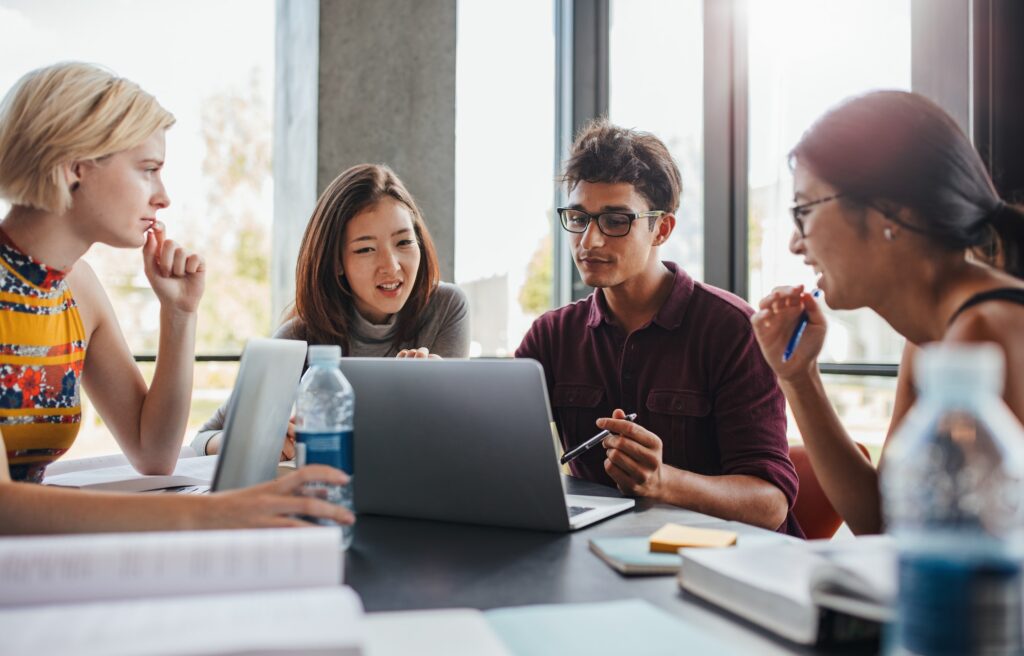 Multiracial young people doing group study at library